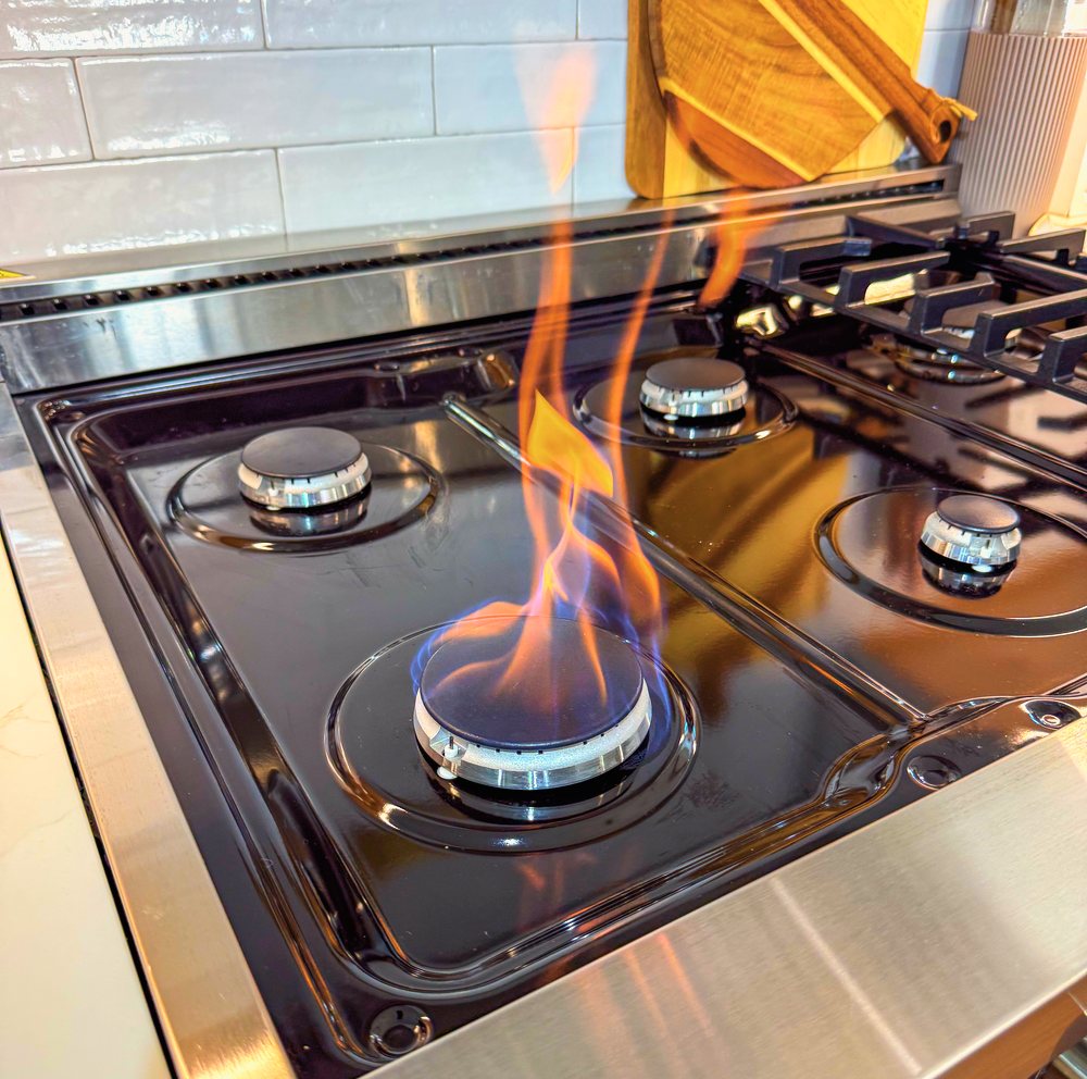 Appliance Rescue Team technician repairing a gas cooktop burner and adjusting the flame in Bergen County, NJ