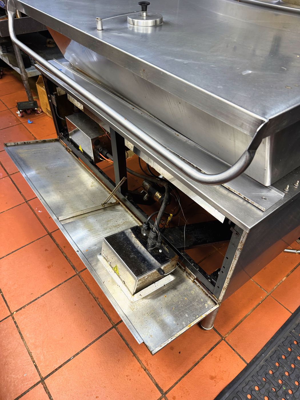 The skillet with the lower panel off. The tilt mechanism and the control boxes both live behind it