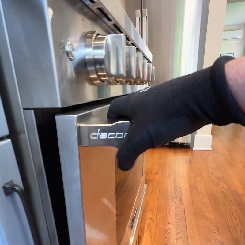 Technician replacing the oven door hinges on a Dacor oven in Alpine, NJ