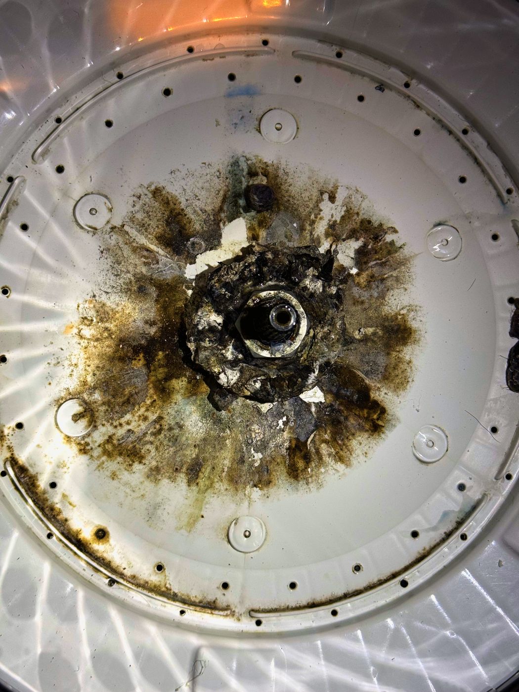The bottom of the tub around the drive hub. The corrosion spreads out from the centre and the coating has lifted away in patches