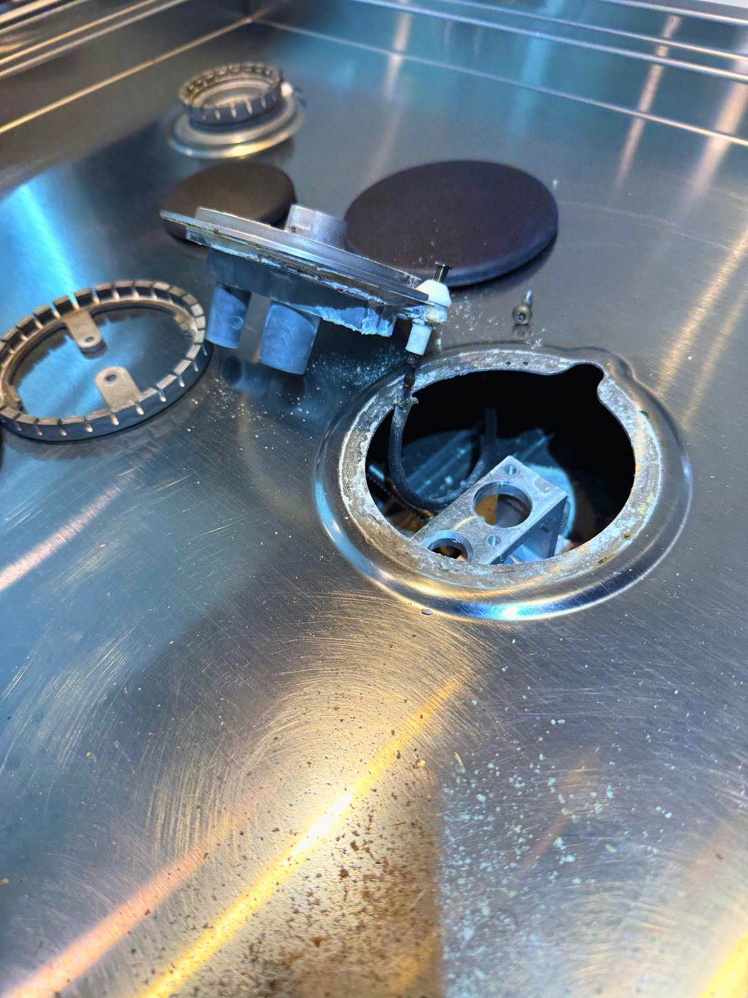How far a burner comes apart to reach that lower tier — cap, head and the well underneath, on every affected burner